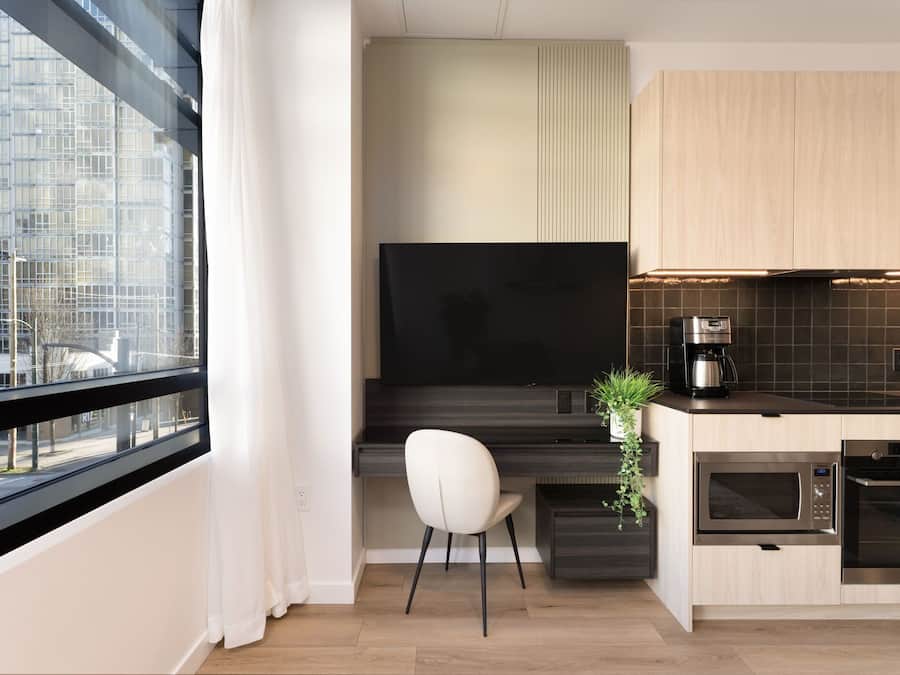 Una cocina moderna con un ventanal grande, un televisor de pantalla plana, una cafetera, un microondas y un horno.