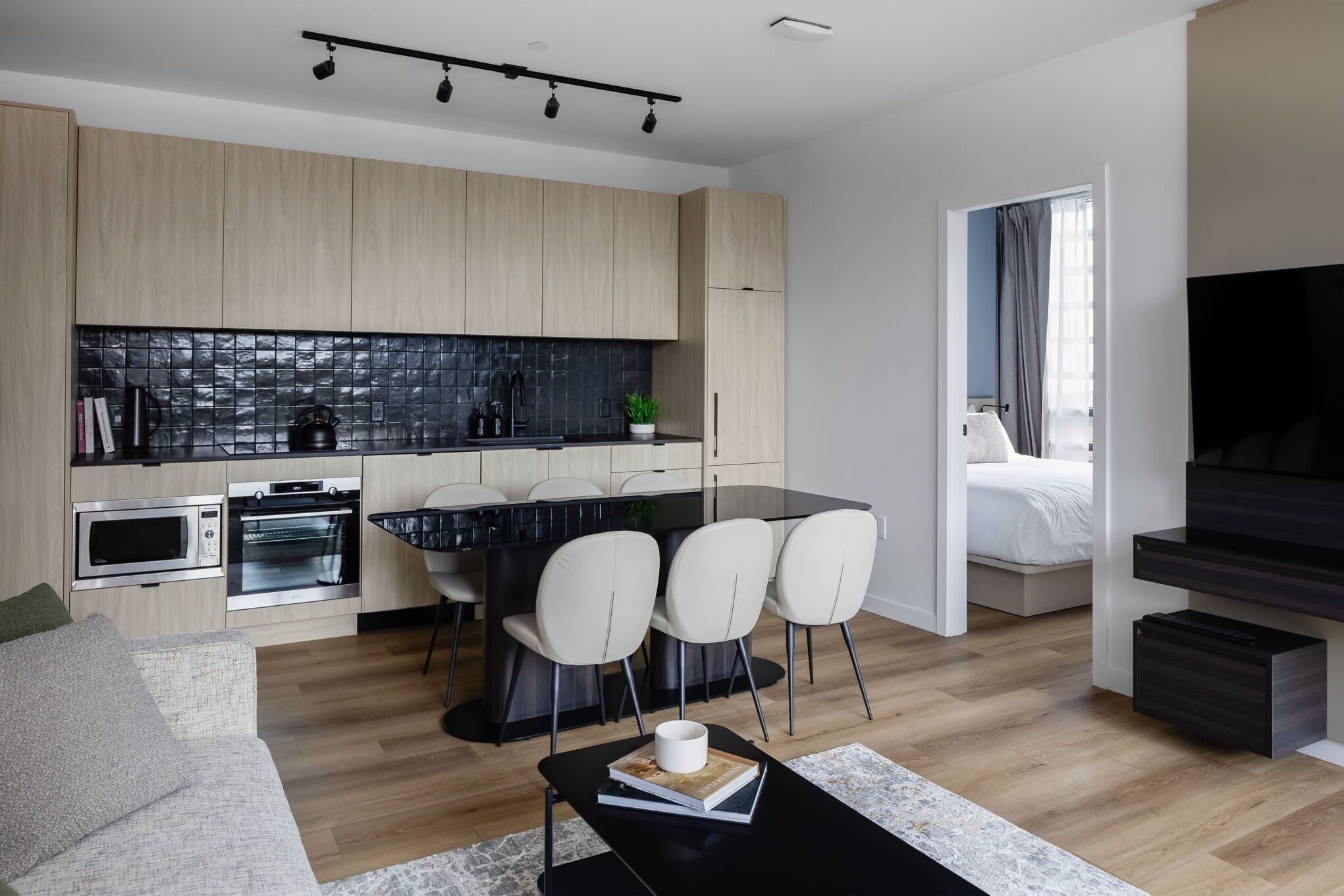 A modern kitchen with built-in appliances, a dining area with chairs, and a living space with a sofa and a coffee table.