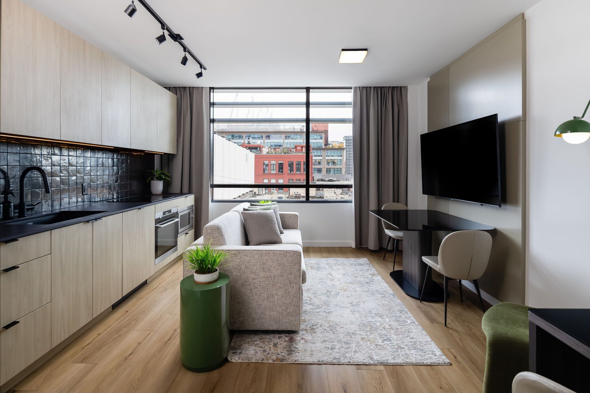 A modern apartment with a kitchen, living area, and a large window with a city view.