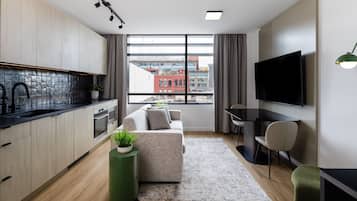 A modern apartment with a kitchen, living area, and a large window with a city view.