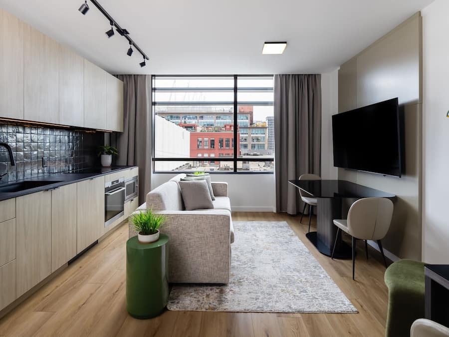 A modern apartment with a kitchen, living area, and a large window with a city view.