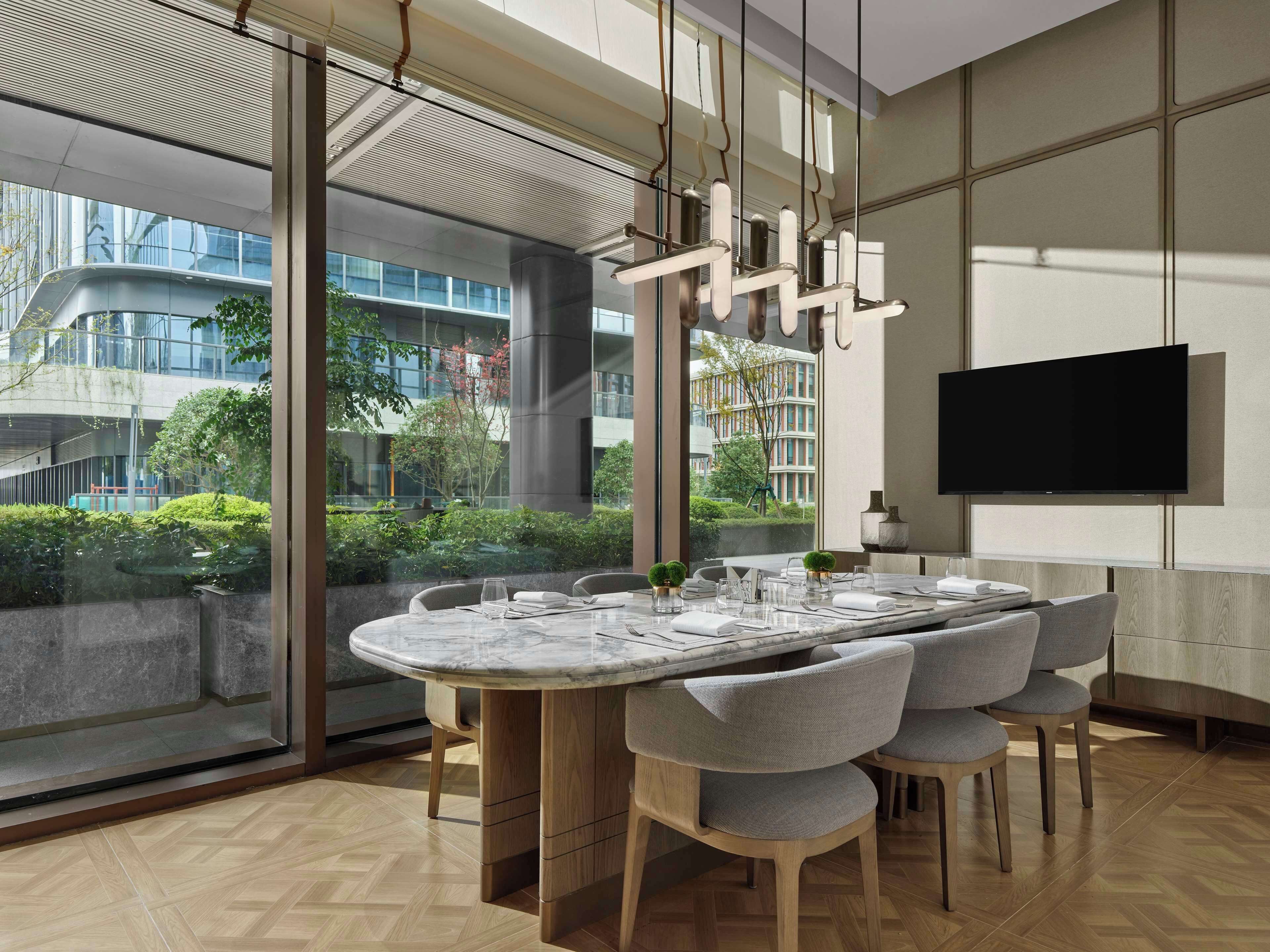 Un'elegante sala da pranzo con un ampio tavolo rotondo, sedie confortevoli e una grande finestra con vista sulla città.