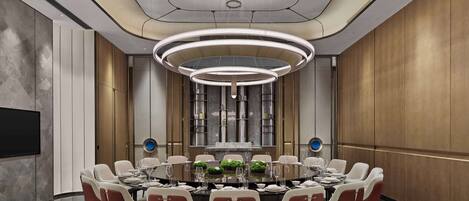 A modern conference room with a round table, red and white chairs, a large TV, and a unique ceiling design.