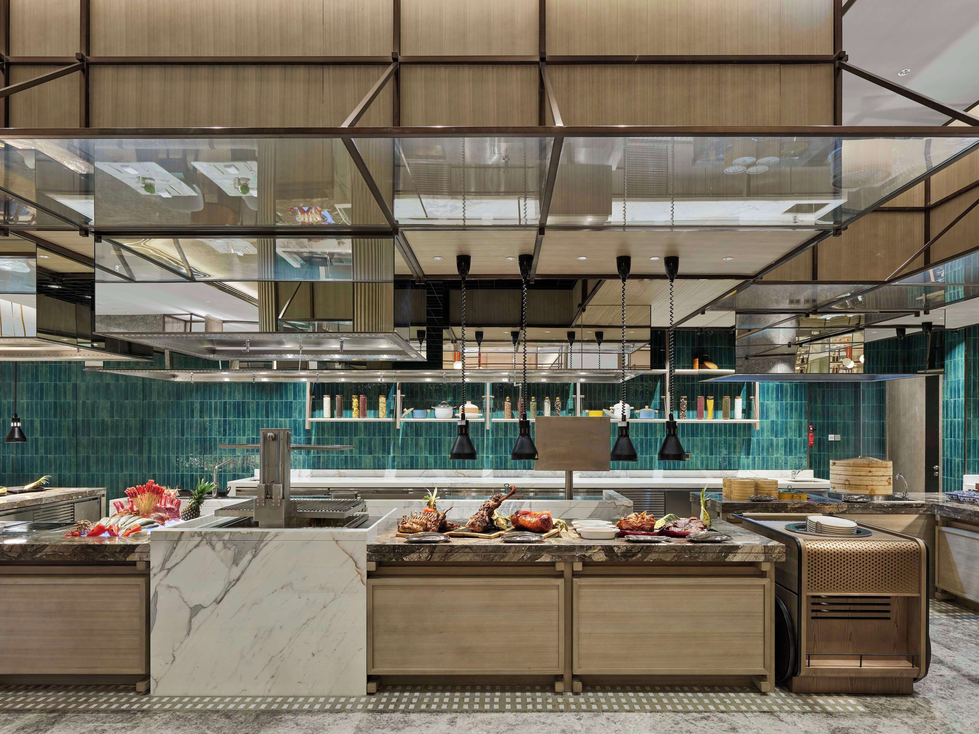 A modern kitchen with a marble countertop, hanging pendant lights, and a tiled backsplash.