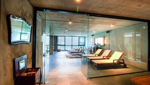 Un interior moderno con pared de vidrio, banco de madera y zona de estar con sillas.