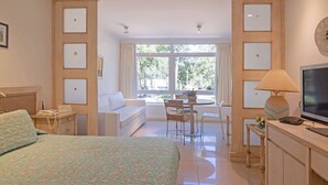 A hotel room with a bed, a desk, a TV, a window with a view, and a sofa. - Oceana Suites Green Park (Punta Ballena)