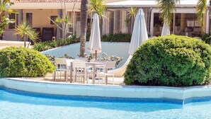 A poolside area with lounge chairs, umbrellas, and a small table. - Oceana Suites Green Park (Punta Ballena)