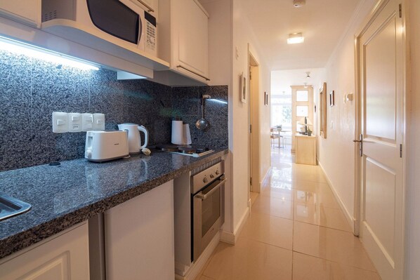 A modern kitchen with granite countertops, a built-in oven, and a microwave. - Oceana Suites Green Park (Punta Ballena)