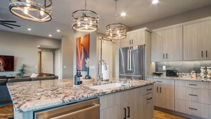 A modern kitchen with granite countertops, stainless steel appliances, and light wood cabinetry. - Luxury Oasis • Pool, Pickleball, Stargazing Views (Kanab)
