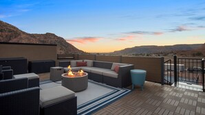 A rooftop patio with a fire pit, outdoor furniture, and a view of the surrounding landscape. - Luxury Oasis • Pool, Pickleball, Stargazing Views (Kanab)