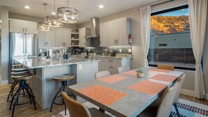 A modern kitchen with a large island, stainless steel appliances, and pendant lighting. - Luxury Oasis • Pool, Pickleball, Stargazing Views (Kanab)