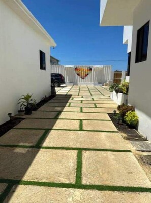 Pathway leads to a building entrance surrounded by white walls and decorative stone slabs.