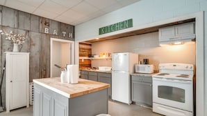 A kitchen with a wooden accent wall, a central island, a refrigerator, a stove, and a microwave. - ATV Adventures Await: Tennessee Riverside Retreat (Briceville)