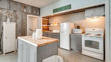 A kitchen with a wooden accent wall, a central island, a refrigerator, a stove, and a microwave.