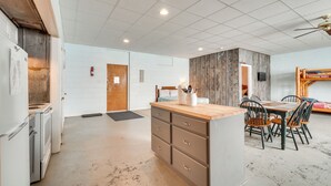 A spacious kitchen with a central island, wooden cabinets, and a dining area with chairs and a table. - ATV Adventures Await: Tennessee Riverside Retreat (Briceville)