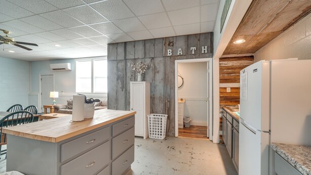 A kitchen with a wooden island, a dining area with chairs, and a laundry basket. - ATV Adventures Await: Tennessee Riverside Retreat (Briceville)