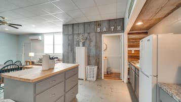 Una cocina con una isla de madera, un comedor con sillas y un cesto de ropa.