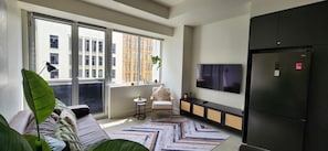Een moderne woonkamer met een bank, een klein tafeltje, een televisie en een koelkast.