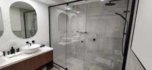 A modern bathroom with a glass-enclosed shower, a white sink, and a wooden vanity.
