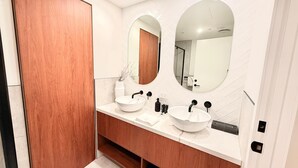 Une salle de bain moderne avec deux vasques, un meuble-lavabo en bois et un grand miroir.