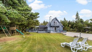 A house with a deck, a swing set, and a grassy yard. - Stunning home in Vestervig with sauna (Vestervig)