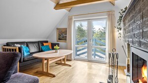 A cozy living room with a black leather sofa, a wooden coffee table, and a fireplace. - Stunning home in Vestervig with sauna (Vestervig)