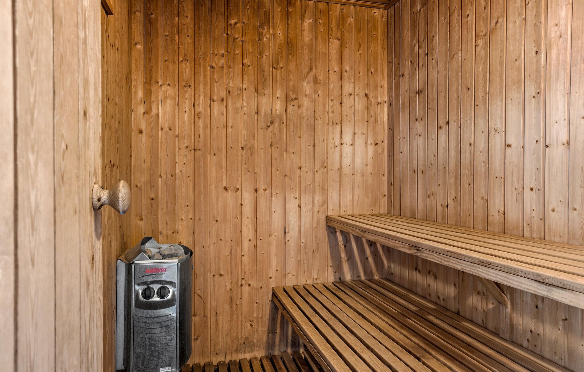 A sauna with wooden walls, a bench, and a sauna heater.