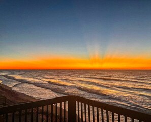 A sunset over the ocean with waves reflecting the sky's colors. - Oceanfront Fun | Balcony at "Osprey's Nest" (North Topsail Beach)