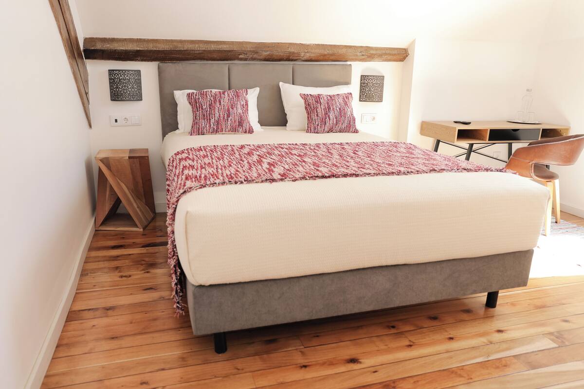 Ein Schlafzimmer mit einem großen Bett, Holzboden, einem Schreibtisch und einem Stuhl.