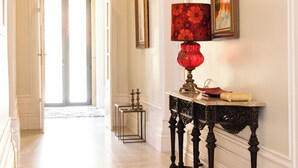 A hallway with a red table lamp, framed artwork, and a door leading to another room. - Quinta dos Tojais (Celorico de Basto)