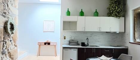 Una cocina moderna con armarios blancos, encimera de mármol y un pequeño comedor con dos sillas grises.