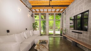 Ein modernes Wohnzimmer mit einem weißen Sofa, einem Marmortisch und einem großen Fernseher, der an einer Steinwand befestigt ist.