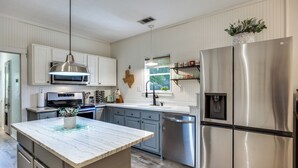 A modern kitchen with white cabinetry, stainless steel appliances, and a marble island. - Historic Downtown Frisco- Walk to Dining- 5m to Toyota Stadium- 12m to Universal (Frisco)