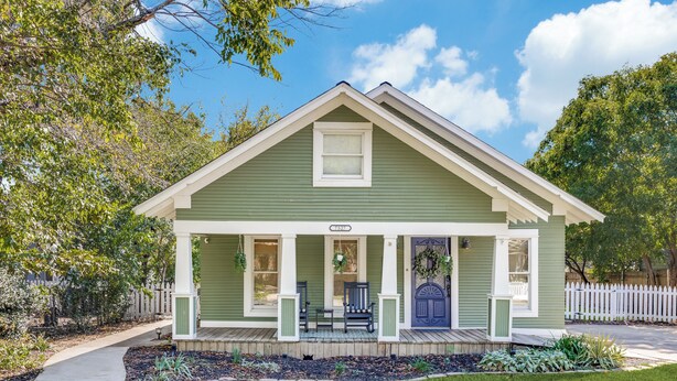 A green house with a porch, a front door, and a small garden area. - Historic Downtown Frisco- Walk to Dining- 5m to Toyota Stadium- 12m to Universal (Frisco)