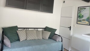 A bedroom with a bed, a large window, a door, and a wall-mounted cabinet. - Studio Vichy (Vichy)