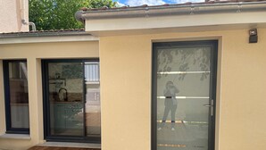A modern building with a glass door, a wooden deck, and a welcome mat with letters. - Studio Vichy (Vichy)