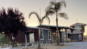 A two-story house with a gravel driveway and a palm tree in the front yard.