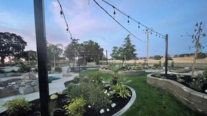 A landscaped garden with a pool, stone structures, and a pergola.