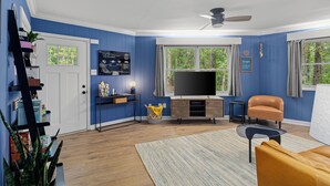 A living room with a TV, sofa, and a ceiling fan. - Fun & Funky Asheville Home with Pool Table, Darts (Arden)