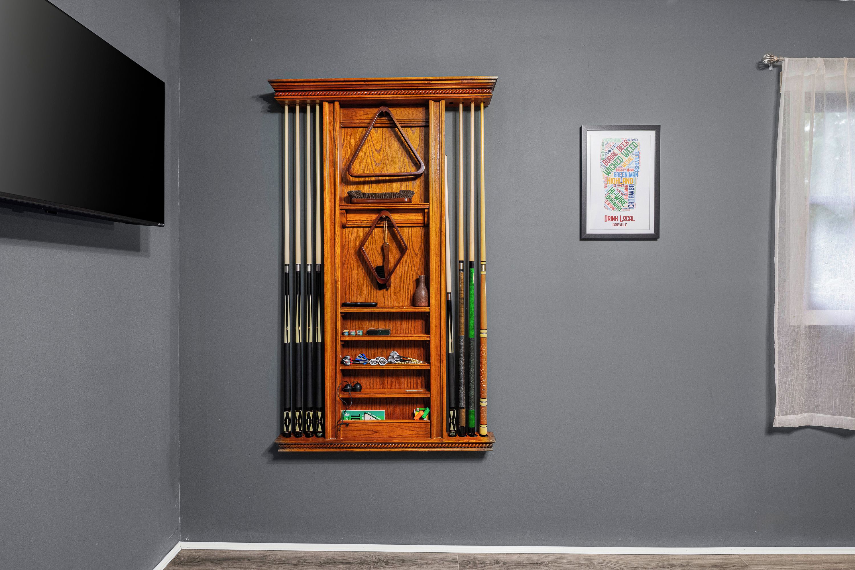 Ein Zimmer mit Poolbillardtisch, gerahmtem Wortwolken-Kunstwerk und Fernseher an der Wand.