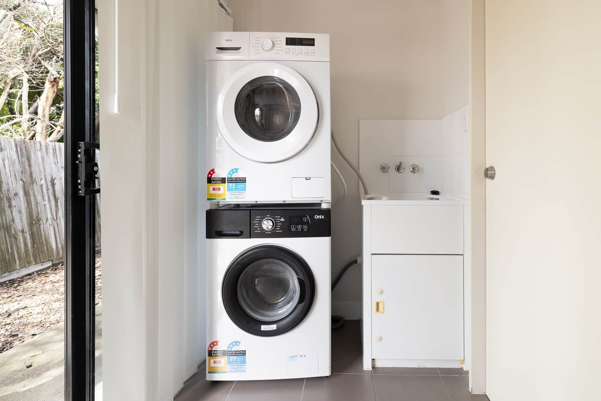 A compact laundry room with a front-loading washer and dryer stacked vertically.