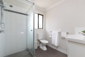 A modern bathroom with a glass shower enclosure, a toilet, and a sink. - Spacious Acacia Ridge 3BR | Private| 6BS3 (Acacia Ridge)