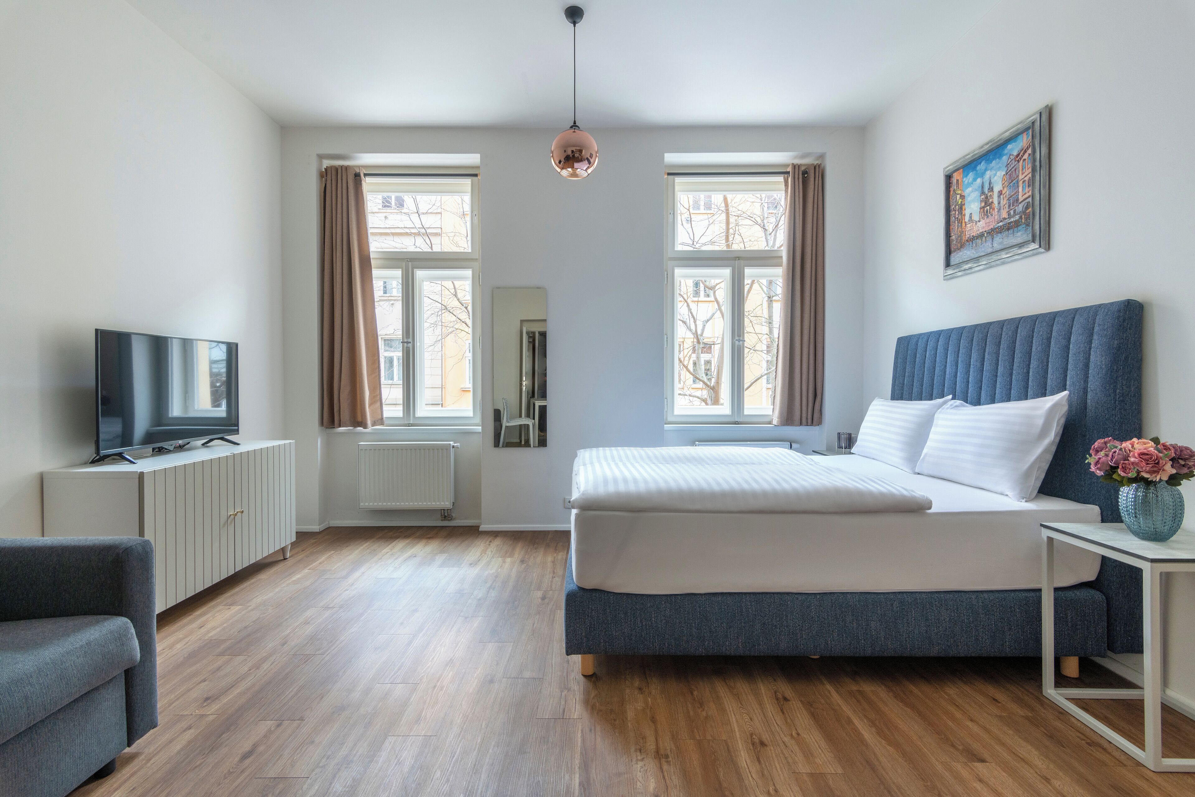 Quarto moderno com uma cama grande, uma televisão em um armário e uma janela com cortinas.