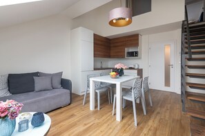 Een moderne leefruimte met een eethoek, een bank, een tafel met stoelen, een keuken en een trap.
