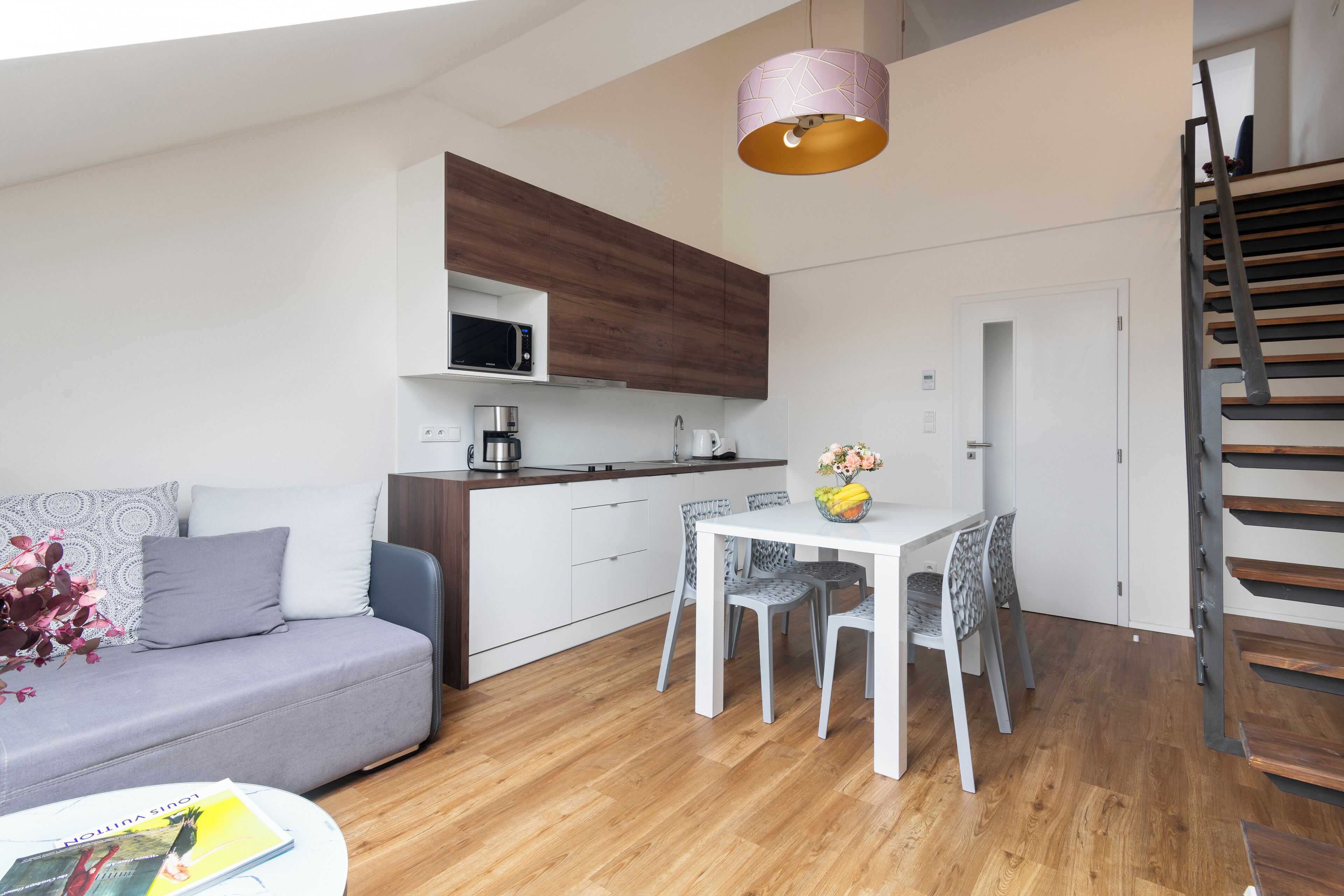 A modern apartment with a kitchen, dining area, and a staircase.