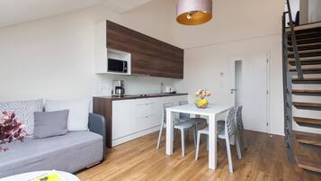A modern apartment with a kitchen, dining area, and a staircase.
