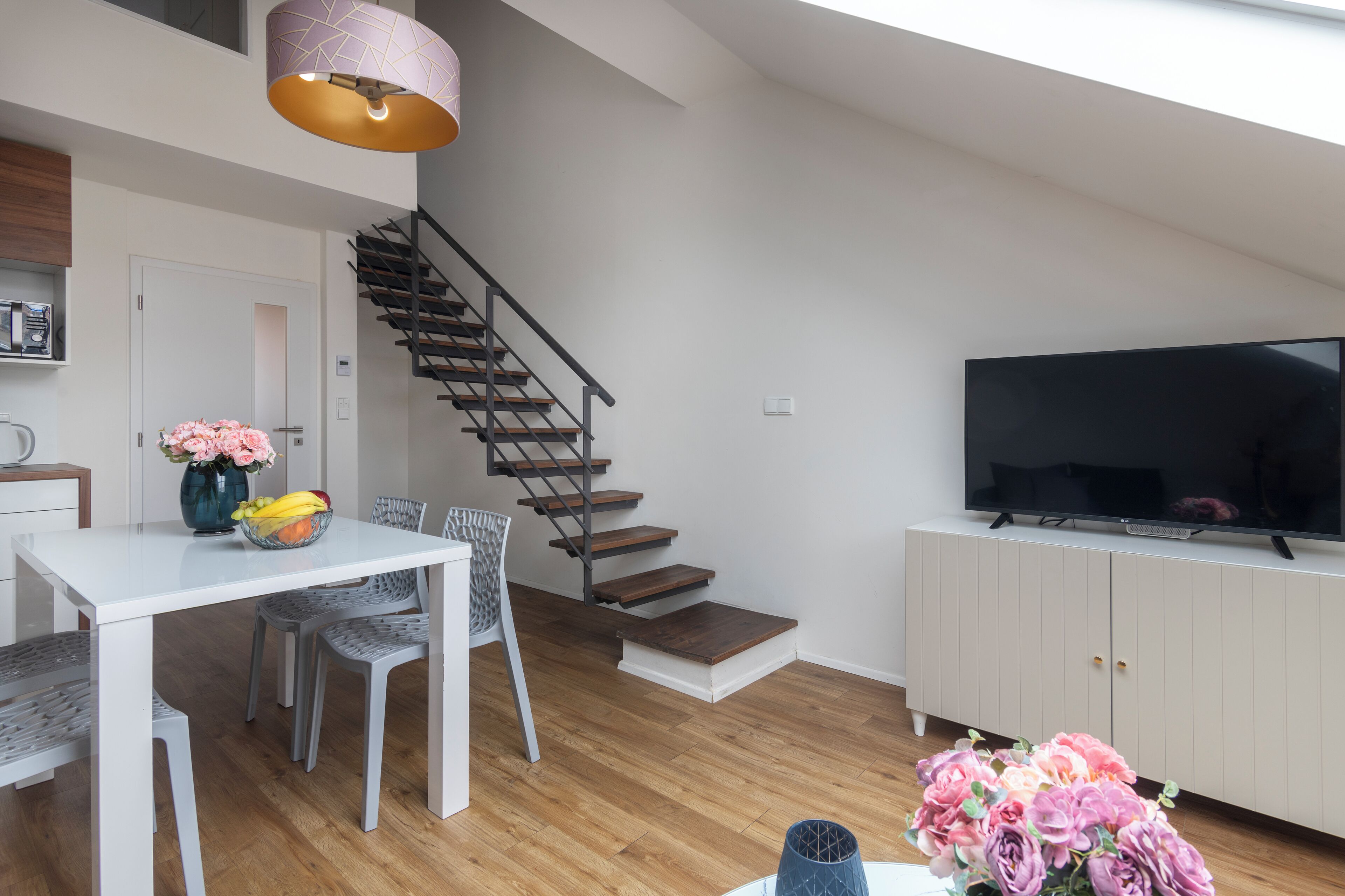 A modern living room with a staircase, a dining area, and a TV.