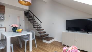 A modern living room with a staircase, a dining area, and a TV.