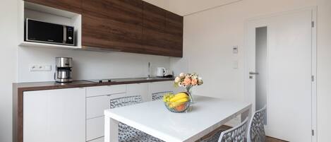 A modern kitchen with a microwave, coffee maker, and a vase with flowers on the counter.