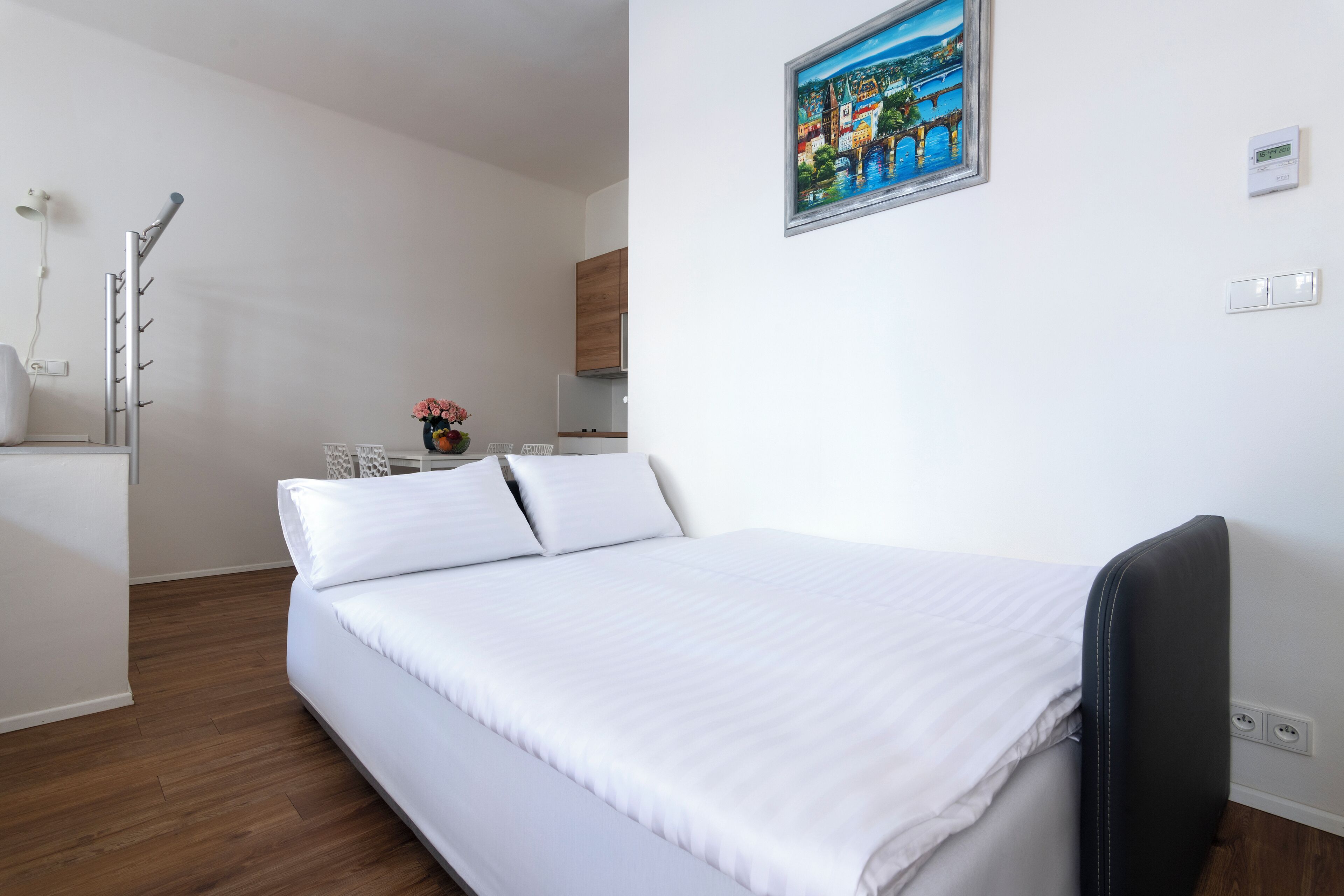 Een moderne hotelkamer met een groot bed, een kleine kitchenette en een schilderij aan de muur.